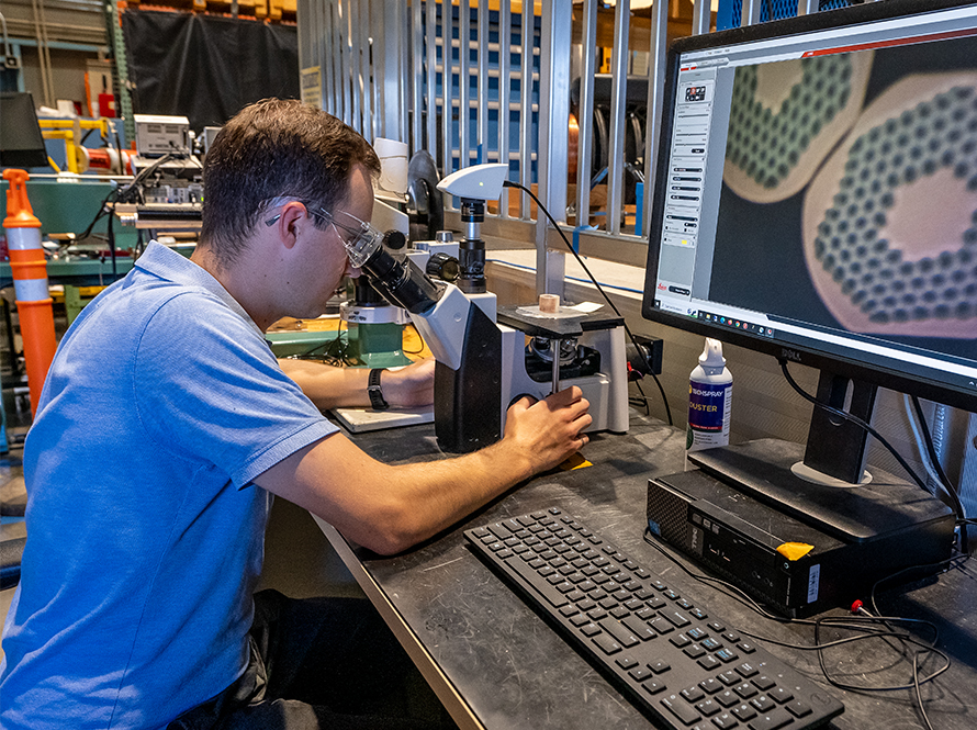 Researcher examines microscope image of conductor cross section
