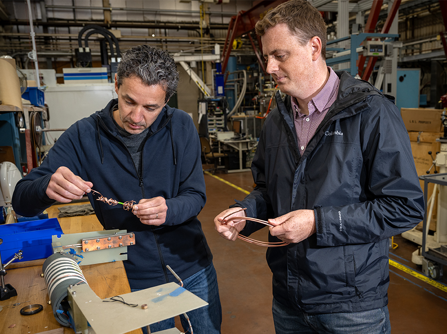 Two researchers examine superconducting cable