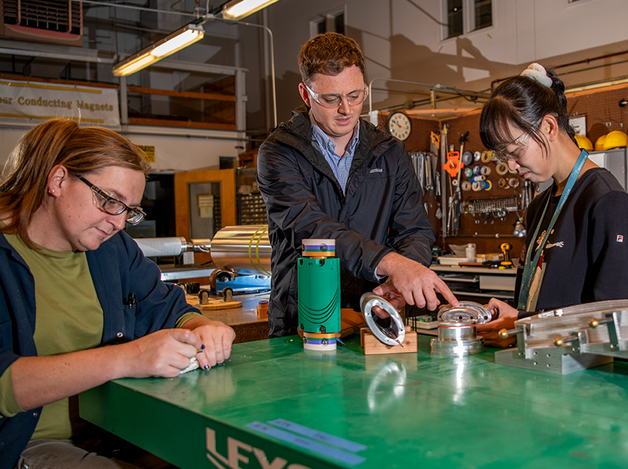 Staff scientist Lucas Brouwer (middle) discusses the design and fabrication of elliptical canted cosine theta magnets with postdoctoral scholar Yufan Yan (right) and technician Simone Johnson (left).